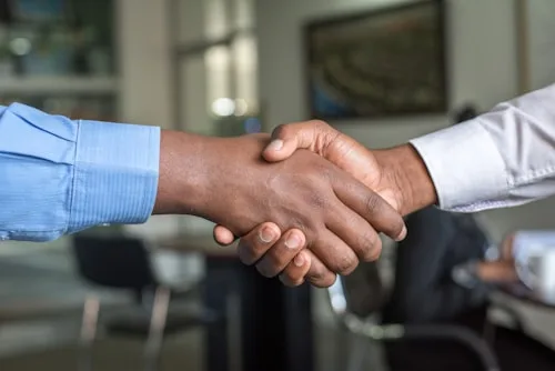Business Meeting | CAQA Creative A handshake symbolizes a successful business deal and collaboration in creative arts.